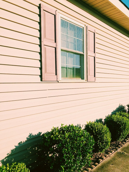 An image of a home with pink paint and a window 